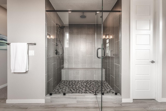 bathroom with a shower stall and baseboards