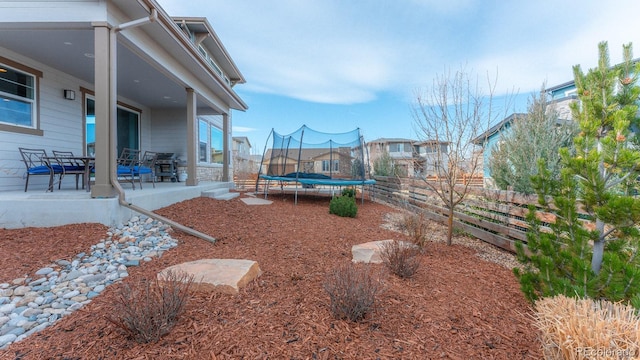 view of yard with a patio area, a trampoline, and fence