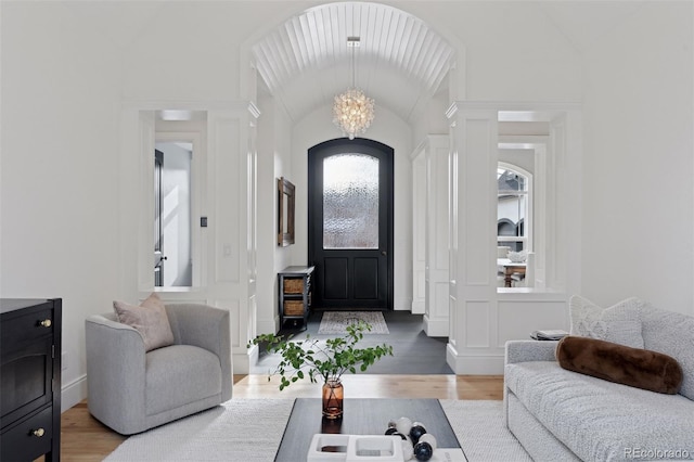 living room with wood-type flooring, lofted ceiling, and a notable chandelier