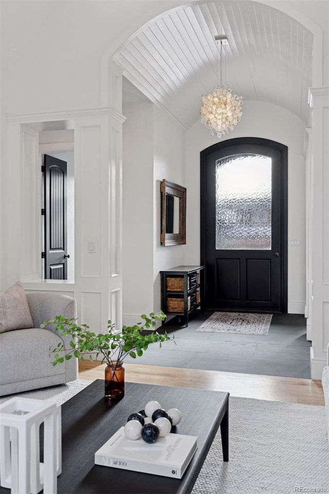 foyer featuring hardwood / wood-style floors, vaulted ceiling, and an inviting chandelier