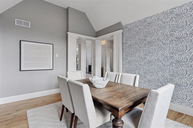 dining space with light wood-type flooring and high vaulted ceiling