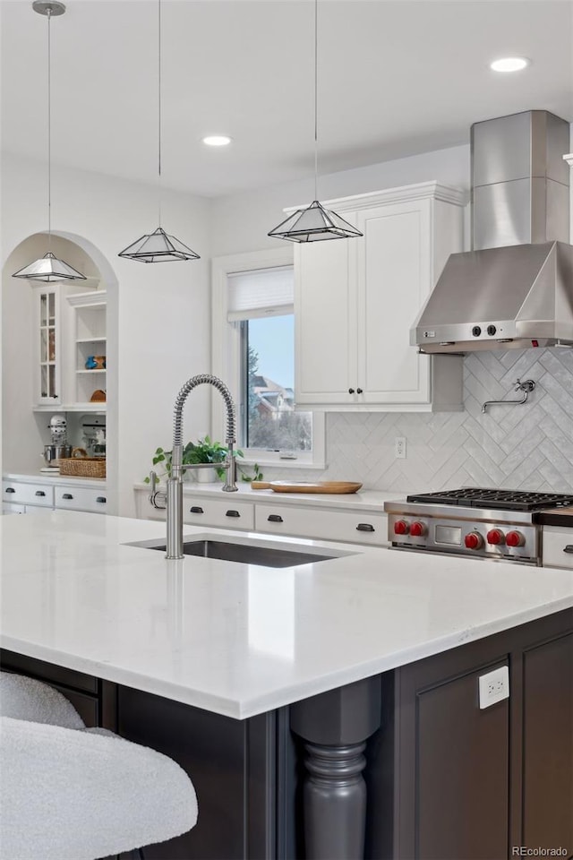 kitchen with white cabinets, pendant lighting, tasteful backsplash, and wall chimney exhaust hood