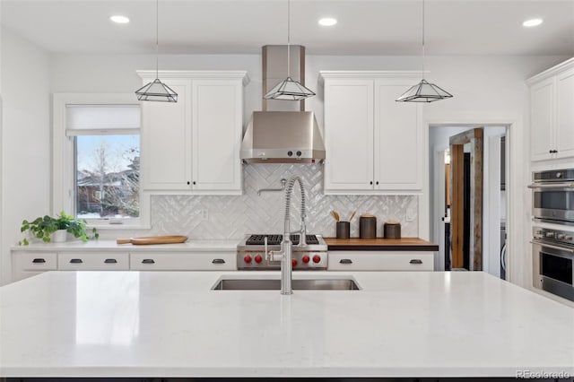 kitchen featuring tasteful backsplash, stainless steel double oven, pendant lighting, a center island with sink, and white cabinetry