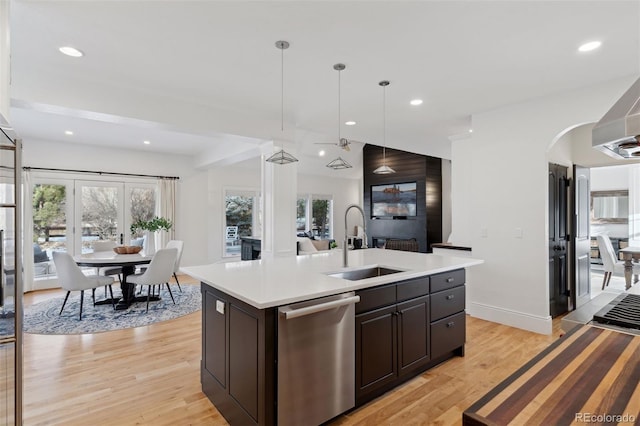 kitchen featuring sink, light hardwood / wood-style flooring, stainless steel dishwasher, pendant lighting, and a kitchen island with sink