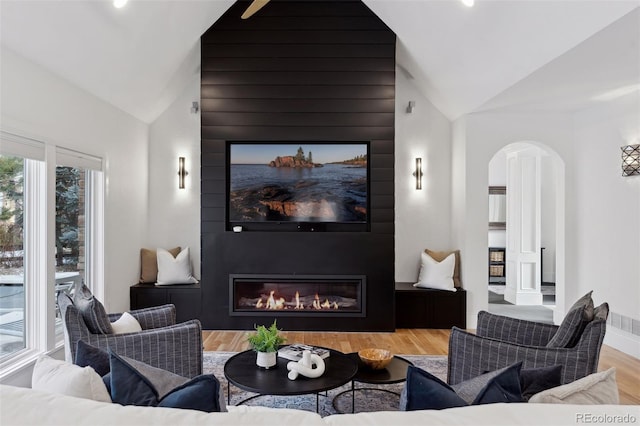 living room with hardwood / wood-style floors, a large fireplace, and vaulted ceiling