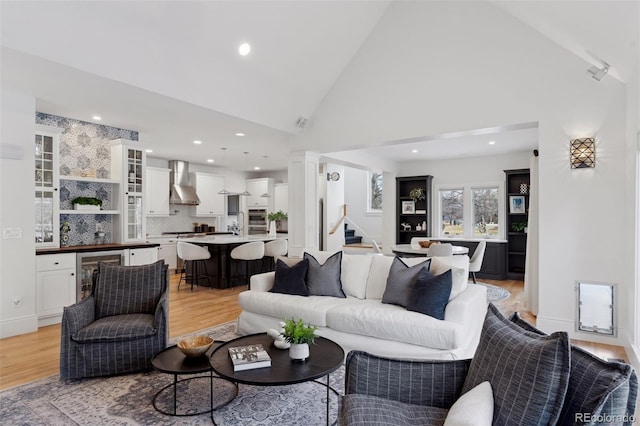 living room featuring high vaulted ceiling, beverage cooler, and light wood-type flooring