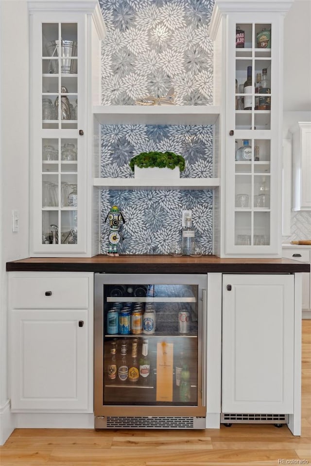 bar featuring white cabinetry, beverage cooler, and light wood-type flooring