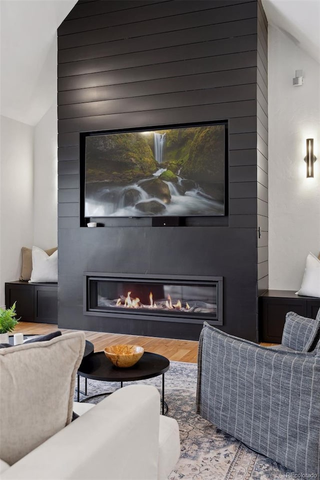 living room featuring wood-type flooring, lofted ceiling, and a fireplace