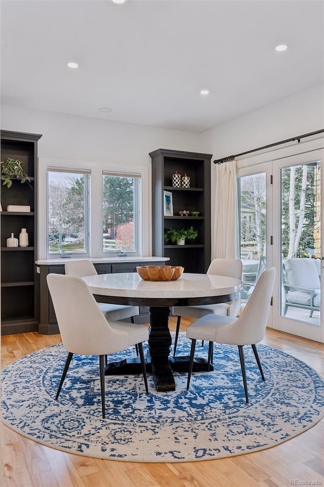 dining area with built in shelves, a wealth of natural light, and light wood-type flooring