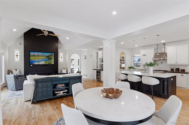 dining room featuring ceiling fan, light wood-type flooring, beverage cooler, and vaulted ceiling