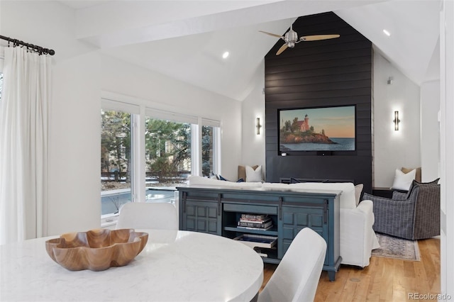 dining space with beamed ceiling, ceiling fan, light wood-type flooring, and high vaulted ceiling