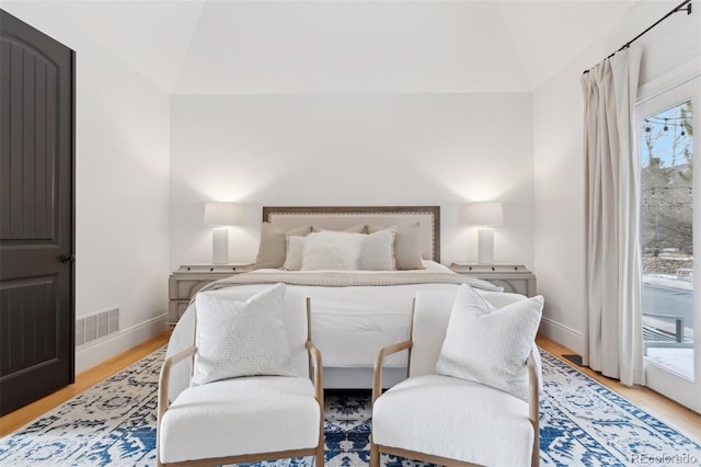 bedroom with multiple windows, light hardwood / wood-style flooring, access to outside, and vaulted ceiling