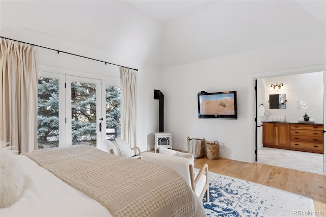 bedroom featuring vaulted ceiling, a wood stove, and light hardwood / wood-style flooring