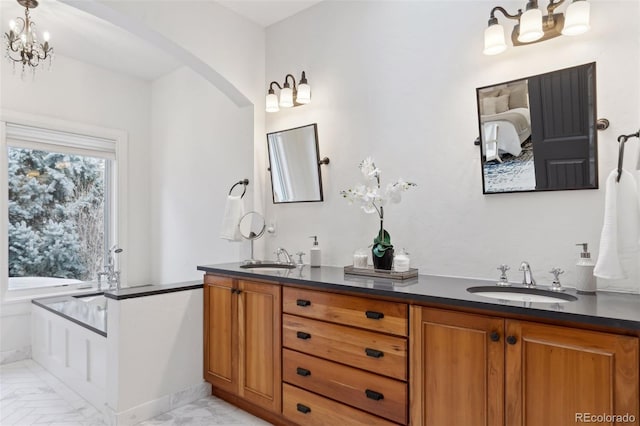 bathroom with a chandelier, vanity, and a bathing tub