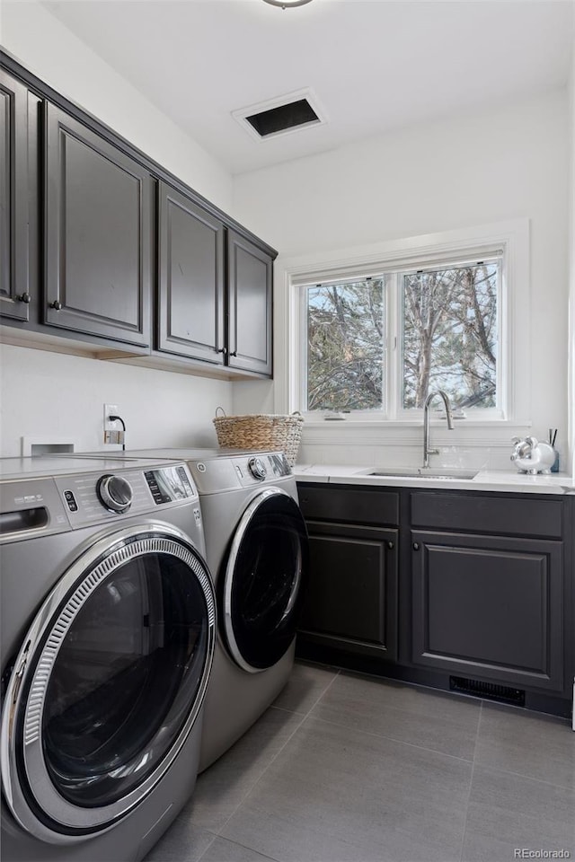 clothes washing area with washing machine and clothes dryer, sink, light tile patterned floors, and cabinets