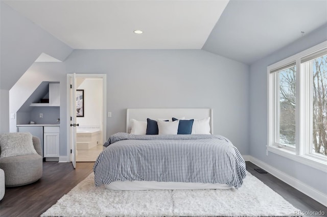 bedroom with ensuite bathroom, dark hardwood / wood-style floors, and lofted ceiling