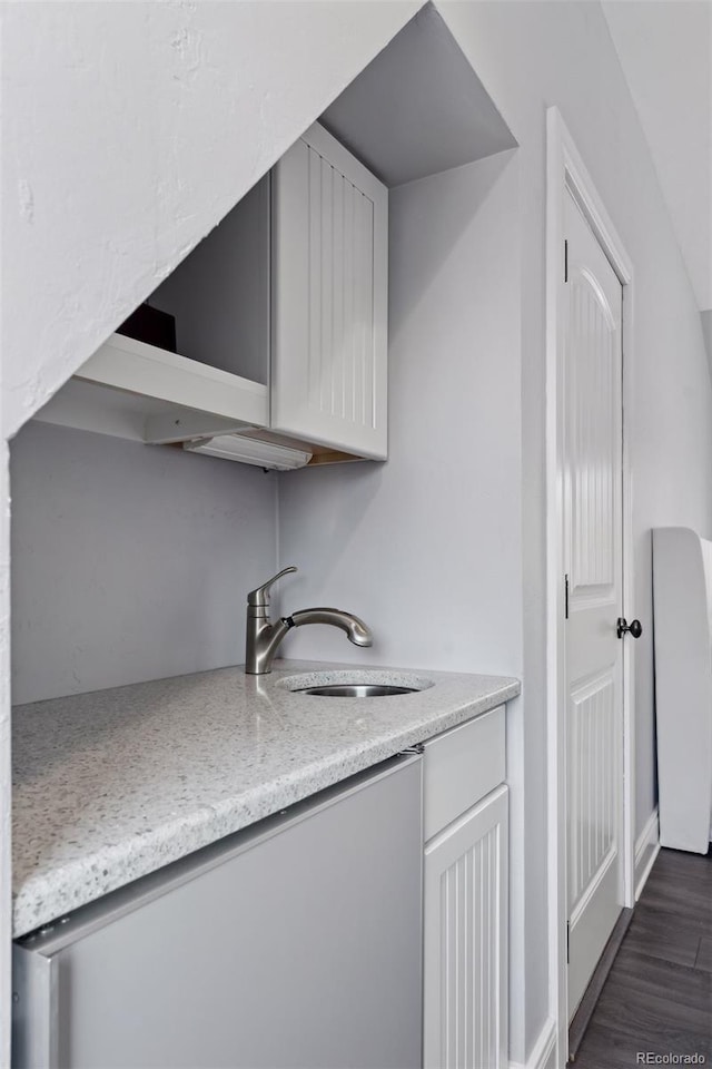 kitchen featuring light stone countertops, sink, and dark hardwood / wood-style floors