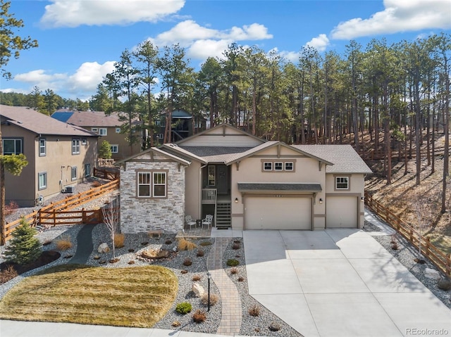 view of front of property with stucco siding, fence, driveway, a garage, and stone siding
