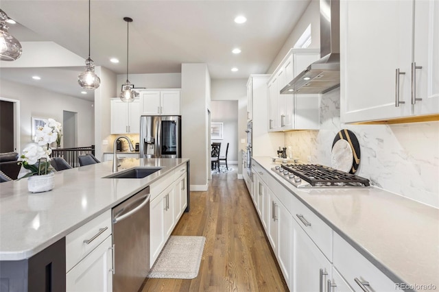 kitchen with a sink, stainless steel appliances, wall chimney exhaust hood, recessed lighting, and backsplash