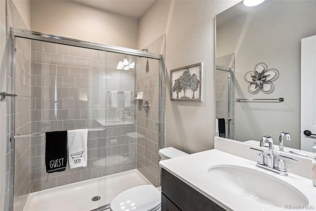 full bath with a textured wall, toilet, a shower stall, and vanity