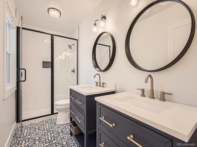 full bathroom featuring toilet, a stall shower, two vanities, and a sink