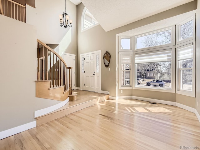 entrance foyer featuring stairs, baseboards, wood finished floors, and an inviting chandelier