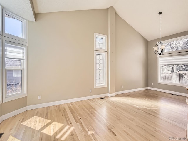 empty room with baseboards, light wood-style flooring, and a notable chandelier