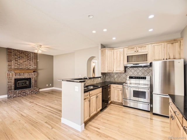 kitchen with tasteful backsplash, open floor plan, stainless steel appliances, light brown cabinets, and a sink