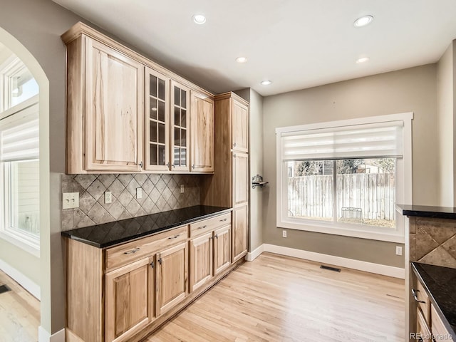 kitchen featuring arched walkways, backsplash, visible vents, and dark countertops