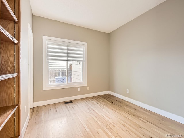 empty room with light wood-type flooring, baseboards, and visible vents