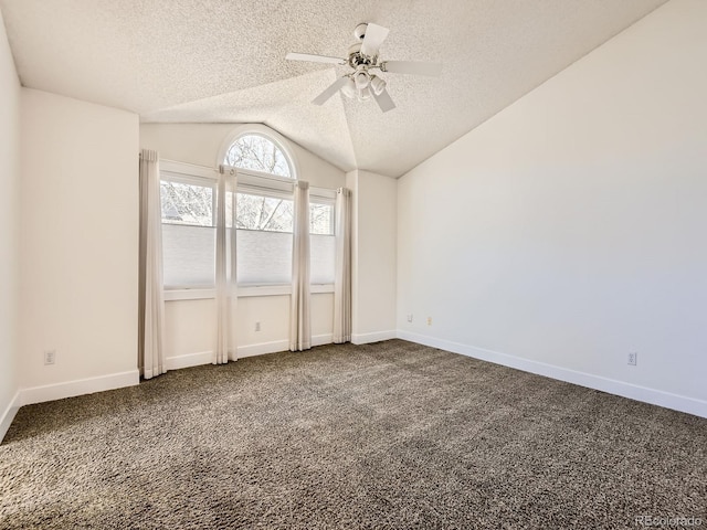 unfurnished bedroom featuring lofted ceiling, dark carpet, a textured ceiling, and baseboards