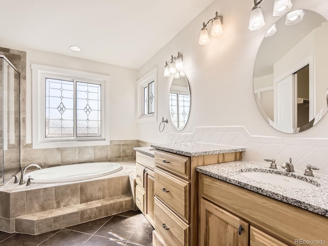 bathroom featuring a shower with door, tile patterned floors, a sink, a garden tub, and two vanities