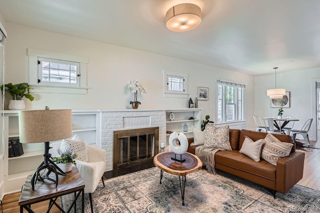 living room featuring wood finished floors, a fireplace, and built in shelves