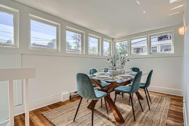 dining space with wood finished floors, baseboards, and a baseboard heating unit