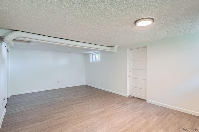 below grade area with wood finished floors, baseboards, and a textured ceiling