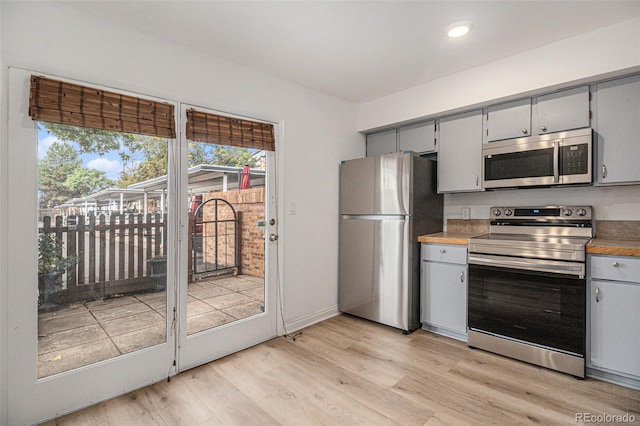 kitchen featuring stainless steel appliances, light hardwood / wood-style flooring, and gray cabinetry