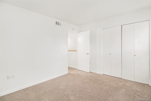 unfurnished bedroom with light colored carpet and a closet