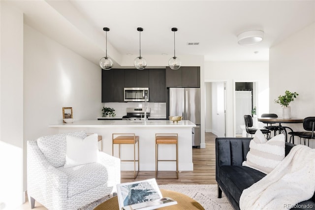 kitchen featuring stainless steel appliances, visible vents, light countertops, dark cabinetry, and decorative light fixtures