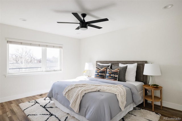 bedroom with ceiling fan, wood finished floors, and baseboards