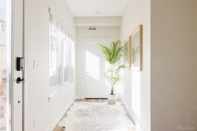 doorway with baseboards, visible vents, and wood finished floors