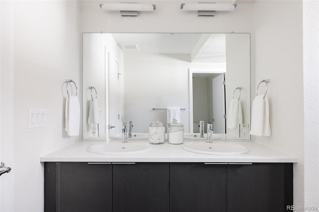 full bath with double vanity, a sink, and visible vents