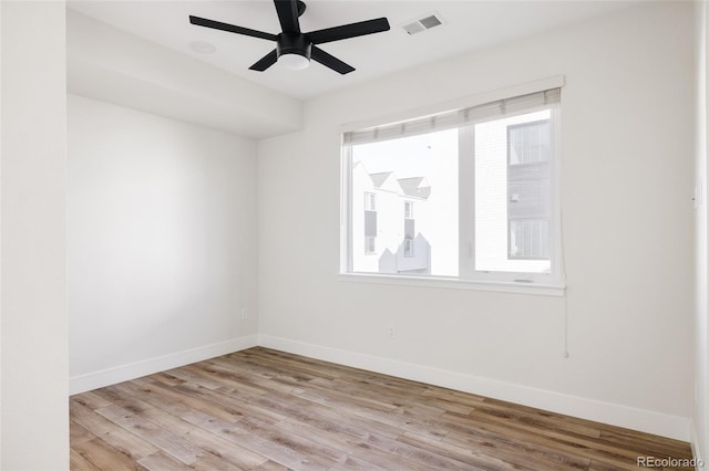 spare room with a ceiling fan, baseboards, visible vents, and wood finished floors