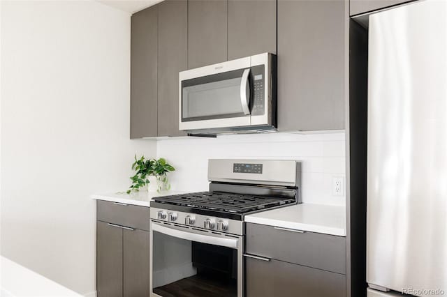 kitchen featuring gray cabinetry, stainless steel appliances, light countertops, tasteful backsplash, and modern cabinets