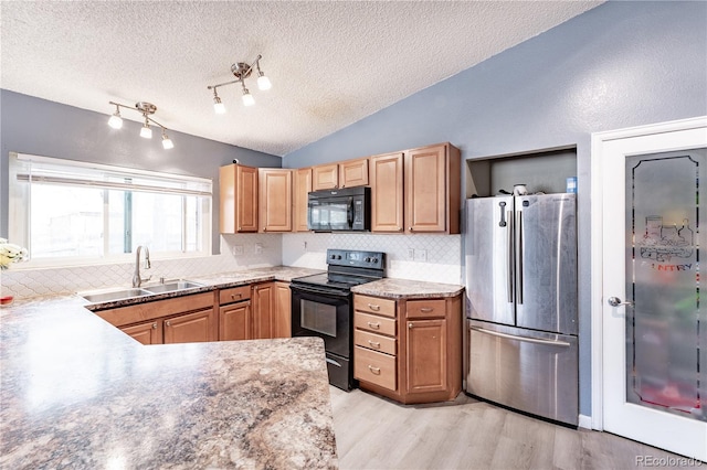 kitchen featuring a textured ceiling, backsplash, black appliances, light wood-style floors, and a sink
