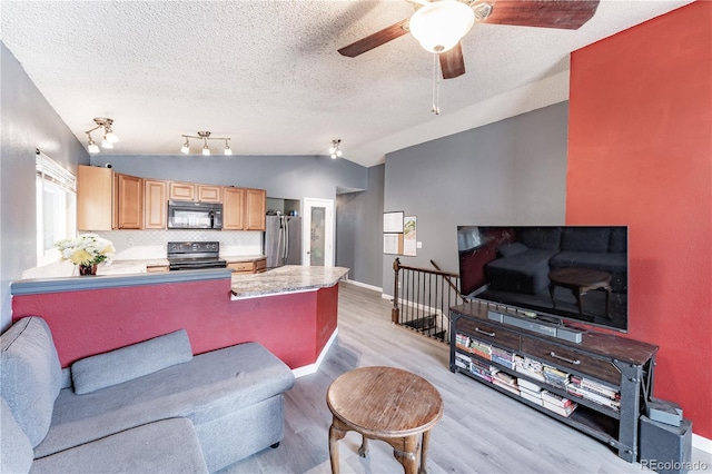 living area featuring baseboards, vaulted ceiling, light wood-style flooring, a textured ceiling, and a ceiling fan