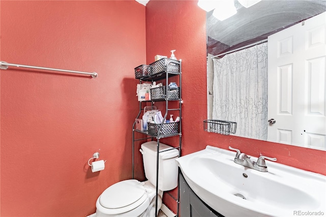 full bathroom with toilet, curtained shower, vanity, and a textured wall