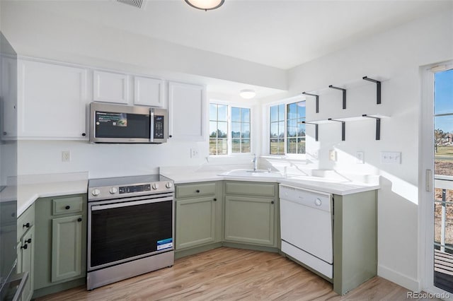 kitchen featuring stainless steel appliances, green cabinets, light hardwood / wood-style floors, and sink