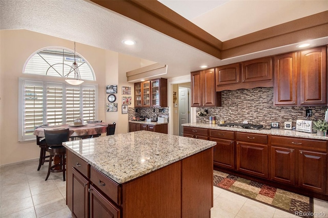 kitchen featuring decorative backsplash, a textured ceiling, light tile patterned floors, a center island, and hanging light fixtures