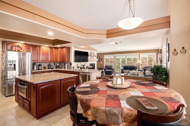 kitchen with a center island, decorative backsplash, light tile patterned floors, appliances with stainless steel finishes, and decorative light fixtures