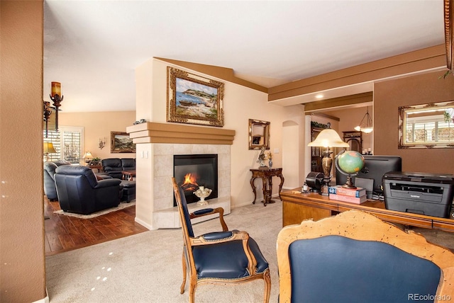 living room featuring a tiled fireplace, light hardwood / wood-style flooring, and vaulted ceiling